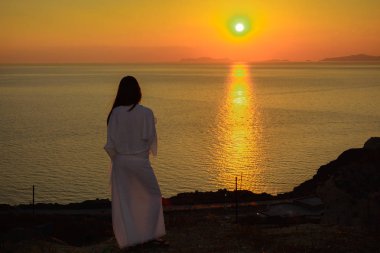 Arka görünümü Santorini'de güneşin parlak ışınları bir beyaz elbiseli bir kadın portresi