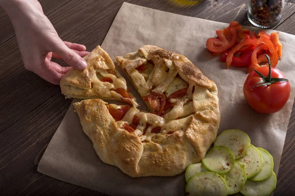 Frauenhände schneiden frischen Gemüsekuchen mit Zucchini, Tomaten und Käse — Stockfoto