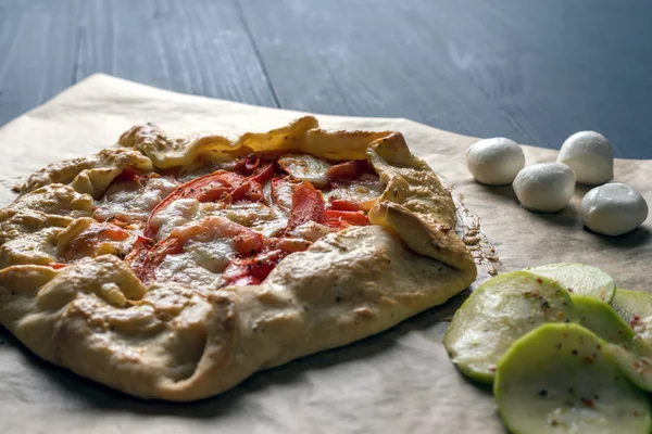 Hausgemachte Galeale mit Tomaten, Mozzarella und Zucchini auf einem Holztisch. — Stockfoto