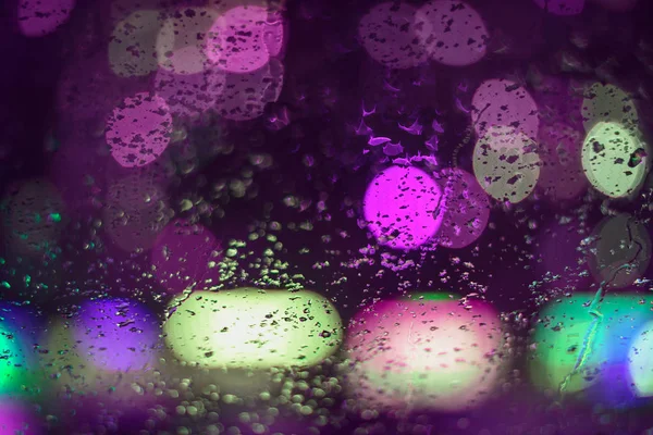 Bild regnet droppar på bilfönstret, stadens ljus på natten i en abstrakt Gud i bakgrunden. grunt djup av fält, grepp, mjukt fokus — Stockfoto