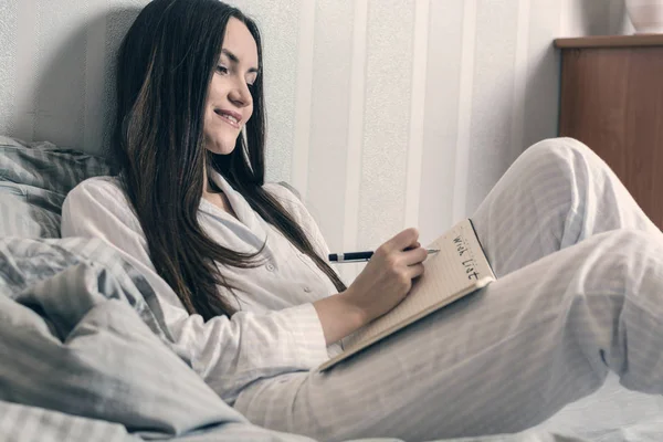Esmer mavi pijama sabah yatakta yatıyor ve bir dilek listesi yapar