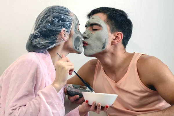 Молода пара цілується і красива маска глина робить здоров'я вдома — стокове фото