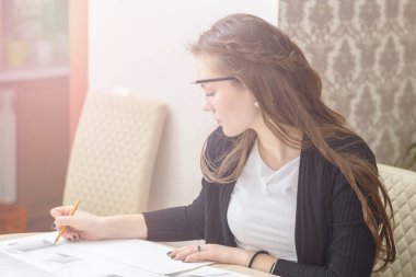 Bir genç kız öğrenci masada nişanlandı frontal portresi çizer skeçler, mimari çizimler, planları. Eğitim ve uygulama
