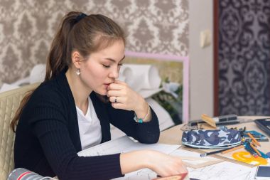 Çizimler için masaüstü oturan beyaz canvas çizim kız öğrenci mimar yoğunlaşmıştır. iç tasarım ve yenileme kavramı. Yan görünüm.