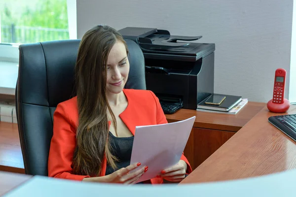 Obchodní žena v červeném obleku sedí v koženém křesle a přečtení smlouvy, Kontrola papíru. — Stock fotografie