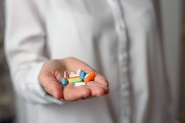 Beyaz bir el, çok renkli hap uzanır ileri.