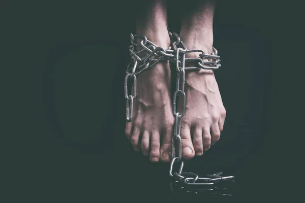 Exhausted female feet with swollen veins associated hanging metal chains closeup over black background, toned in retro film — Stock Photo, Image