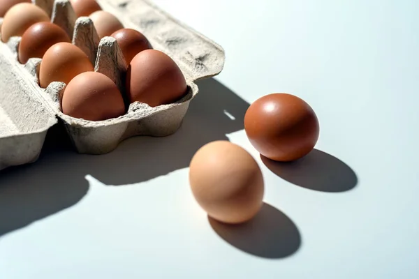 Recycled paper container on white table with rustic brown eggs