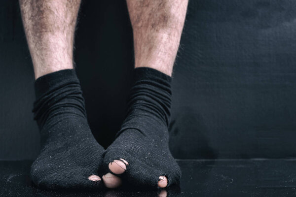 Image under the film, legs in black holes socks. the concept of poverty, bankruptcy, poor, debt