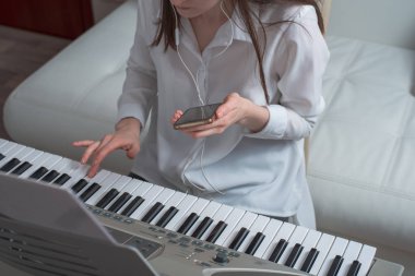 Genç kadın öğrenmek synth smartphone kullanarak oynamak için