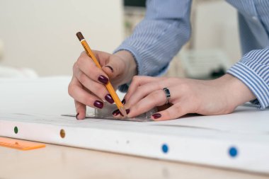 Bir kalem ve cetvel, elleriyle close-up bir beyaz kağıt üzerine çizmek
