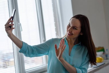 Genç bir kız bir selfie evde mutfak iç ön kamera alır, memnuniyetle el aç