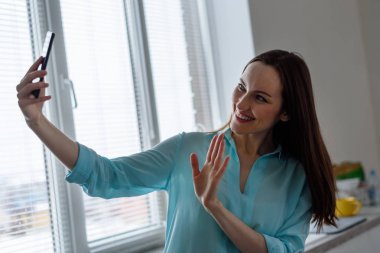 Genç bir kız bir selfie evde mutfak iç ön kamera alır, memnuniyetle el aç