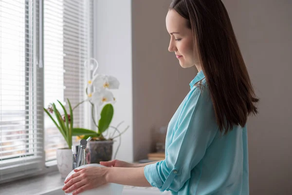 Housewife washes dishes in front of the window in the kitchen, in the soft light of morning — Stock Photo, Image