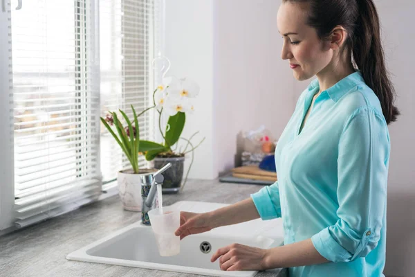 Retrato de una mujer joven ganando un vaso de agua limpia en la cocina frente a la ventana — Foto de Stock