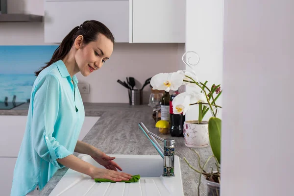 Mujer con ropa de casa limpia el fregadero en la cocina después de la limpieza —  Fotos de Stock