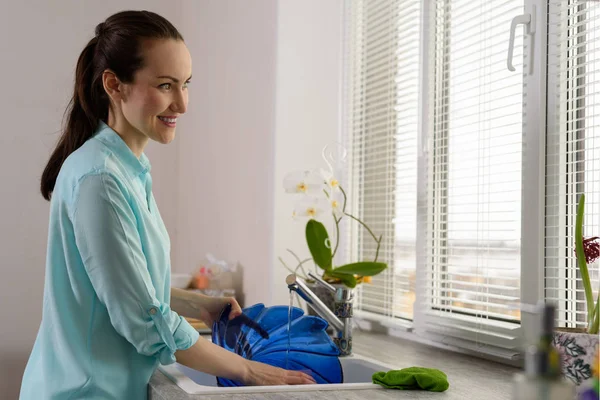 Lavados de ama de casa sonrientes en placa azul fregadero de cocina — Foto de Stock