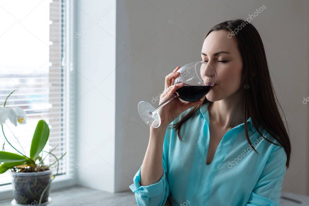 Young woman drinking a glass of red wine. concept of rest after cleaning