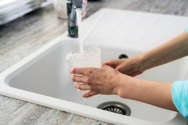 Plastik kap mutfak lavabo musluk suyu kazanıyor ile eller Close-Up