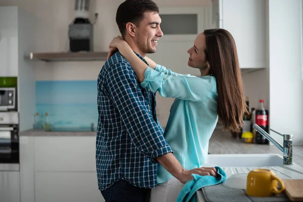 Ευτυχισμένο ζευγάρι αγκαλιάζει και να βλέπουν κάθε άλλο στο εσωτερικό του μια νέα κουζίνα, ευτυχία σε ένα νέο σπίτι. — Φωτογραφία Αρχείου