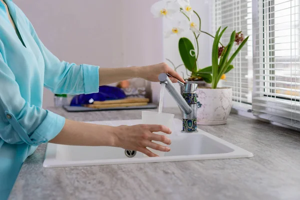 Przycięte zdjęcie kobiecych rąk przy filiżance rozlewa filtrowana woda z kranu w kuchni — Zdjęcie stockowe