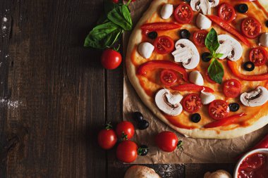 Mantarlı, zeytinli, kiraz domatesli ve kahverengi ahşap kaplamalı hazırlıksız pizzanın yatay görüntüsü.