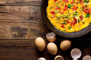 Kahverengi ahşap zemin üzerinde yeşil, domates ve kabak tohumlarıyla çırpılmış yumurta ve çırpılmış yumurta.