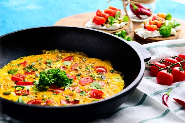 Dökme demir tepside sağlıklı bir kahvaltı. Çırpılmış yumurta, yeşil ve domates, krem peynirli sandviç, pesto ve vişneli domates. — Stok fotoğraf