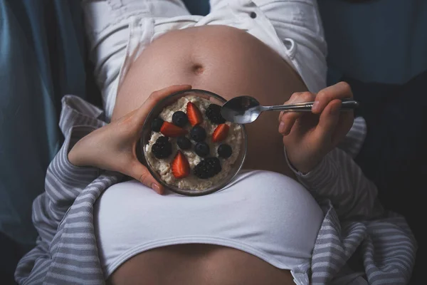 Immagine ritagliata di donna incinta a letto con farina d'avena con bacche, sana colazione a letto, gravidanza sana — Foto Stock