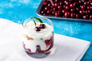 Kirazlı tatlı, Yunan yoğurdu ve camlı granola mavi arka planda beyaz peçete.
