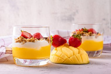 Mangolu krem peynir, fırında yulaf ezmesi ve pembe arka planda çilek.