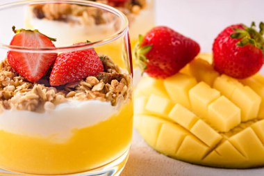 Tatlı, ricotta peyniri, mango, granola ve pembe arka planda çilek..