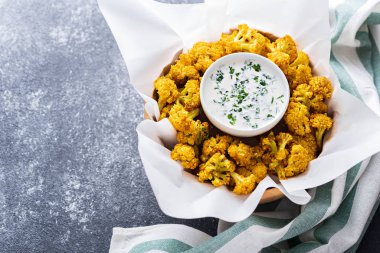 Gri arka planda ekşi krema soslu karnabahar.