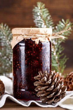 vertical image of jam from young pine cones on wooden background