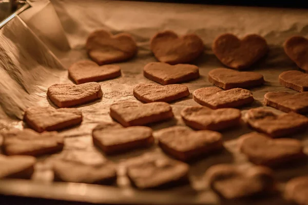 Cuisson de biscuits maison coeurs sur papier parchemin blanc dans le four — Photo