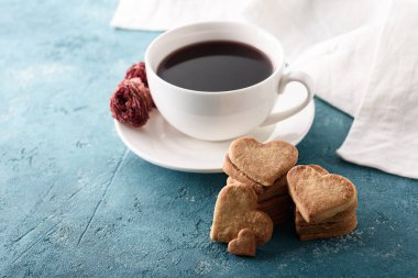 Ev yapımı kurabiye kalbi olan kırmızı çay, mavi arka planda beyaz havlu.