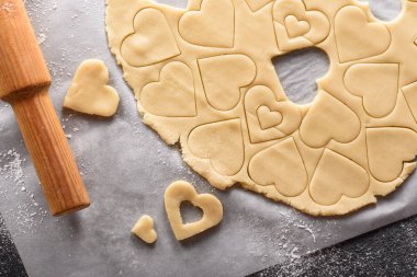 Kesik şekilli kurabiye hamurunun üst görünümü ve kağıt üzerinde merdane.