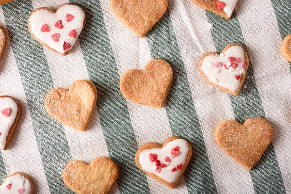 Biscuits maison coeurs décorés avec glaçage et garniture de pâtisserie sur serviette en tissu blanc et vert — Photo