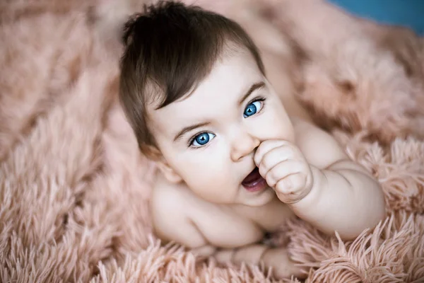 Beautiful blue eyed baby on fluffy light orange blanket — Stock Photo, Image