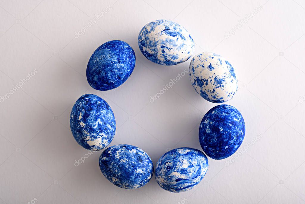Easter eggs in the color of the year-classic blue with gradient effect are arranged in circle on white background