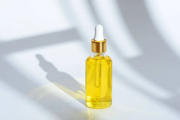 Cosmetic oil in glass bottle with pipette on white background with shadow — 스톡 사진