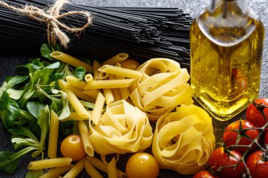 Akşam yemeği için yakın plan spagetti fettucine, domates, mısır salatası, gri arka planda zeytinyağı.