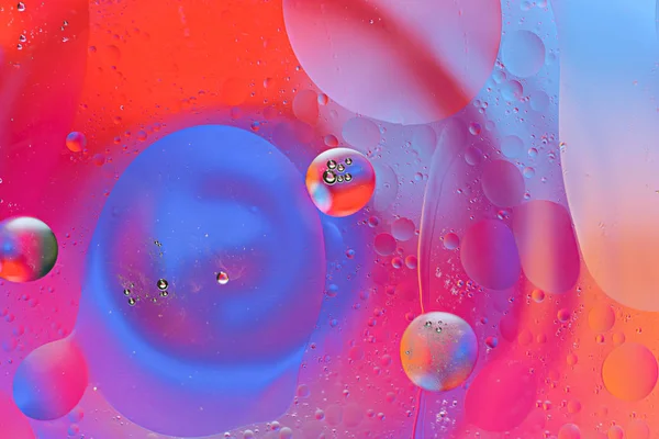 Πολύχρωμες φυσαλίδες και κηλίδες του πετρελαίου σταγόνες στην επιφάνεια του νερού σε έγχρωμο φόντο — Φωτογραφία Αρχείου