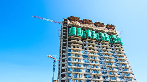 Proceso de construcción de edificio de varios pisos con grúa de construcción sobre fondo azul cielo — Foto de Stock