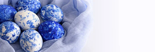 Білі великодні яйця з класичним синім візерунком і градієнтним ефектом у тканинному рушнику на білому тлі — стокове фото