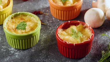 casserole with chicken and mushrooms under cheese crust in multicolored cocoanuts on gray background with vegetables