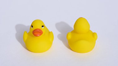 Beyaz arka planda gölgeli iki küçük sarı oyuncak ördek yavrusu