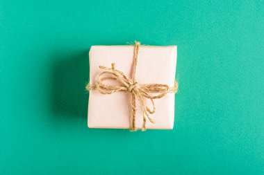 Yeşil arka planda fiyonklu yumuşak pembe hediye kutusu