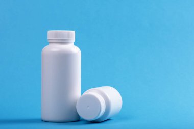 Damgalamak için mavi arka planda iki beyaz tıbbi konteynır şişesi.