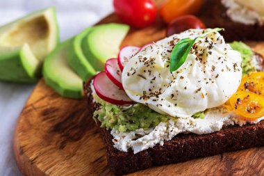 Yakın plan vejetaryen tostu haşlanmış yumurta, süzme peynir, avokado ve sebze hafif atıştırmalık, sağlıklı kahvaltı konsepti.